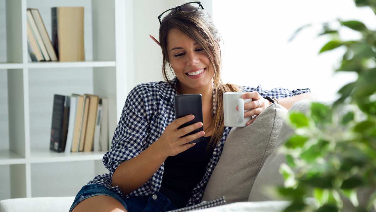 Woman drinking tea and using a smartphone
