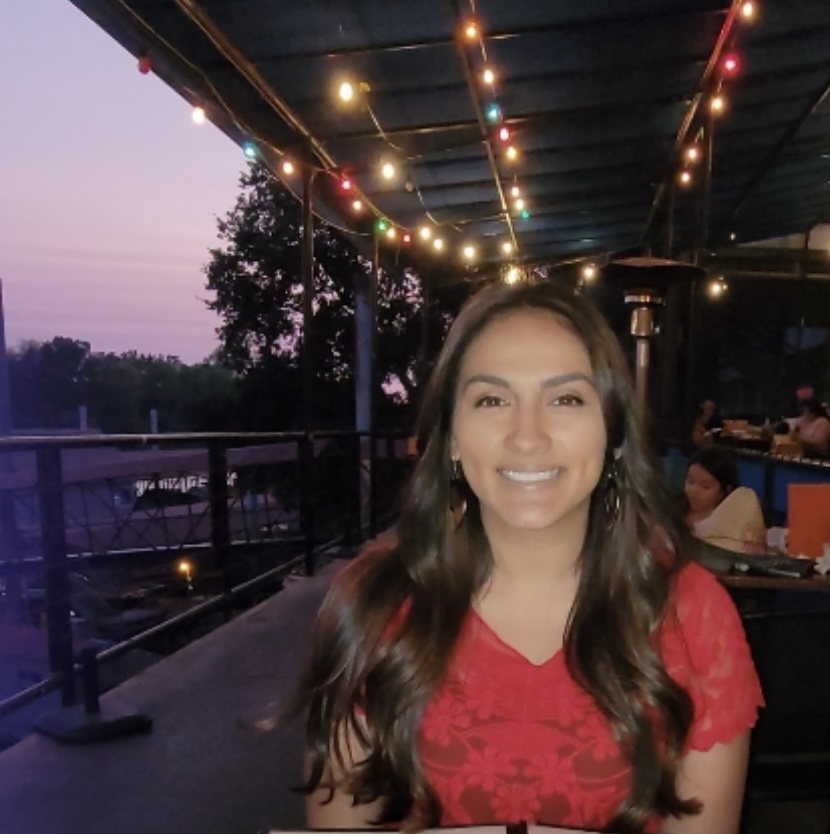 Smiling young woman sitting in an outdoor restaurant with colourful fairy lights