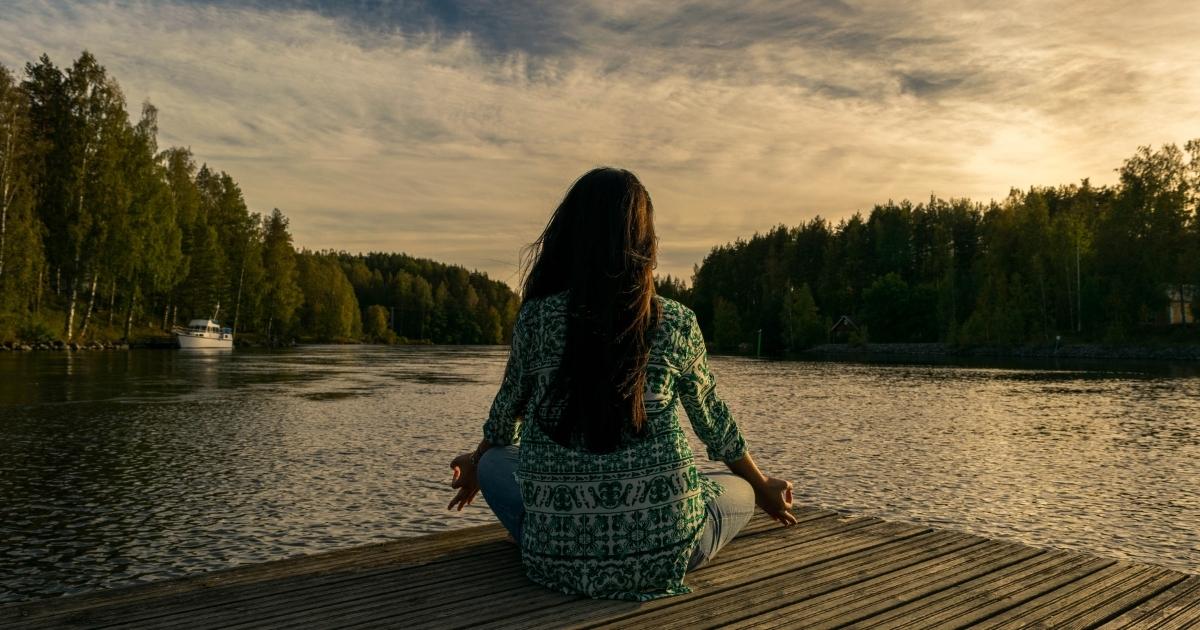 Woman meditating by the lake